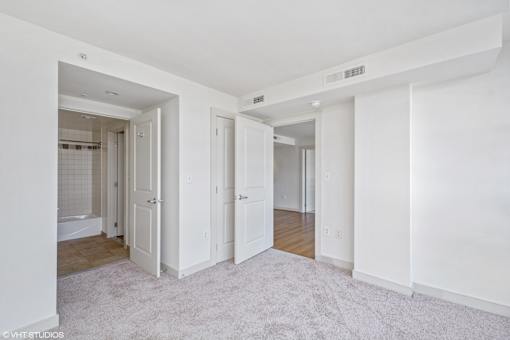 A white room with a carpeted floor and a doorway leading to another room.