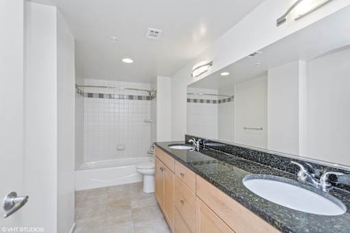 A bathroom with a black granite countertop and a white sink.