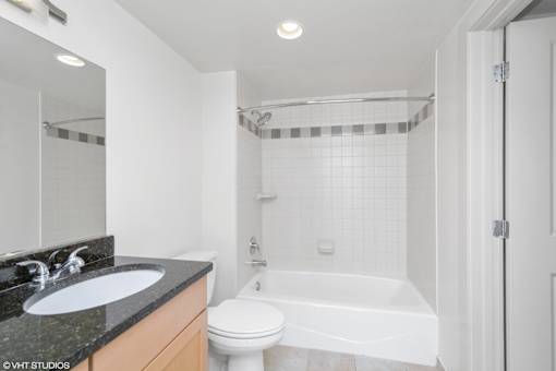 A white bathroom with a black granite counter top.
