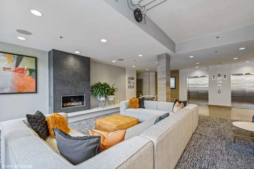 A modern living room with a grey sofa, a fireplace, and a painting on the wall.