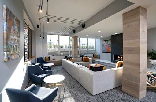 A modern living room with a large couch, chairs, and a fireplace.