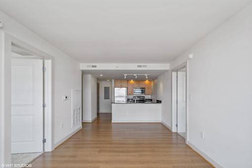 A long, empty hallway with a kitchen area at the end.