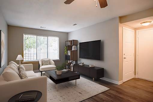 A living room with a white couch, a black television, and a wooden floor.