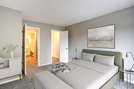 A bedroom with a bed, nightstand, and a painting on the wall.