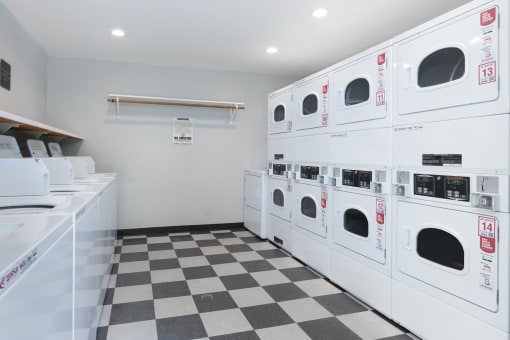 a laundry room with white washers and dryers on a checkered floor
