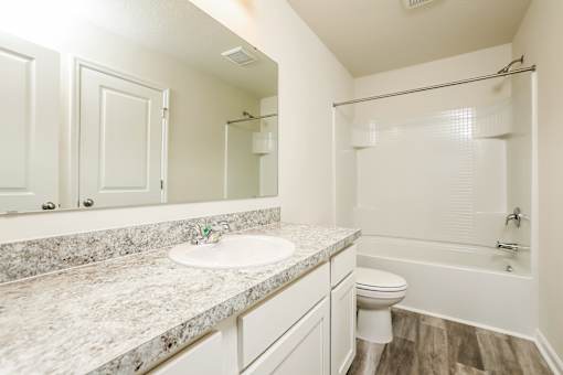 A bathroom with a marble countertop and white fixtures.