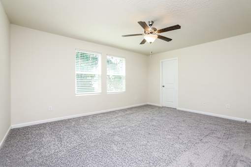 A room with a ceiling fan and carpeted floor.