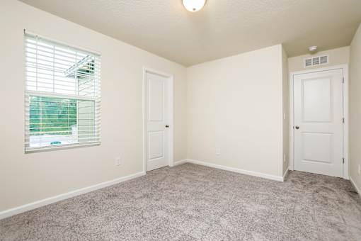 A room with a carpeted floor and two doors.