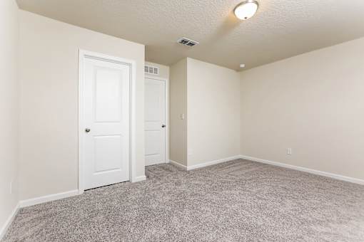 A room with two doors and carpeted floor.