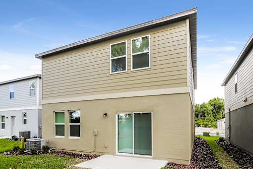 A beige house with a grey roof and a green door.