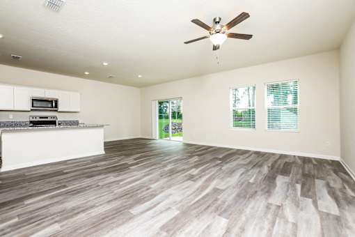 A spacious room with a ceiling fan and wooden flooring.