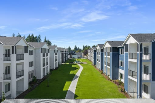 an exterior view of a row of apartment buildings with a green lawn in the middle,
