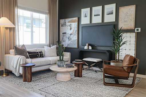 A living room with a white sofa, a grey couch, a brown chair, and a grey rug.