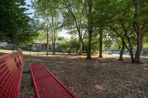 Pet-Friendly Apartments in Lawrenceville– Park on Sweetwater – a red bench in a park with trees