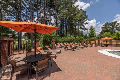 Pet-Friendly Apartments in Lawrenceville– Park on Sweetwater – a patio with chairs and umbrellas and a pool