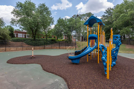 Lawrenceville, GA Apartments – Park on Sweetwater – a playground at a park with a blue and yellow slide