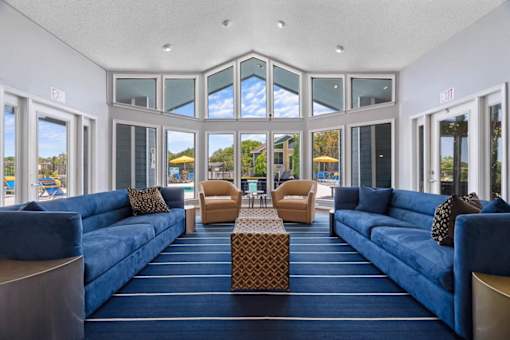 A large room with blue couches and a table in the middle.