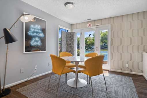 A room with a table and chairs and a painting on the wall.