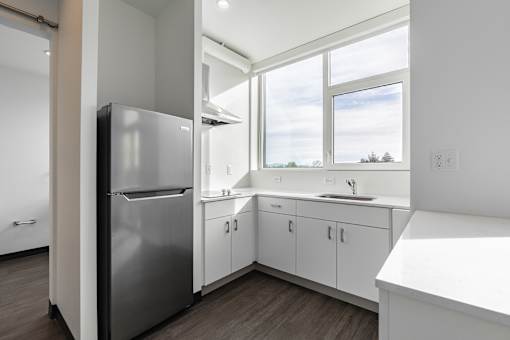 A kitchen with a stainless steel refrigerator and white countertops.