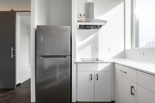 A modern kitchen with a stainless steel refrigerator and white cabinets.