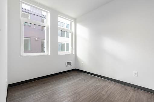 A room with a window and a wooden floor.