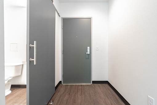 A hallway with a grey door and a white door.