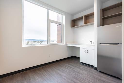 A kitchen with a stainless steel refrigerator and wooden flooring.