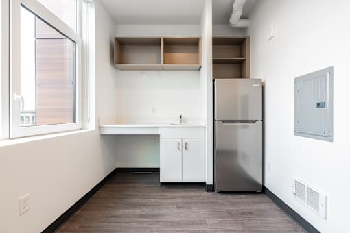 A kitchen with a refrigerator, sink, and cabinets.