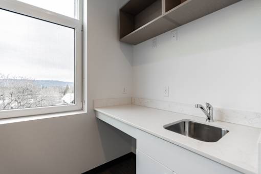A kitchen with a window overlooking a snowy landscape.