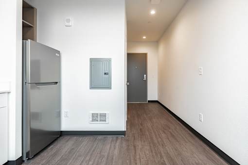 A kitchen with a refrigerator and a wood floor.