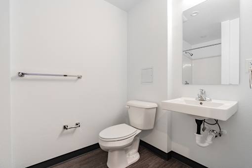 A white toilet sits next to a white sink in a small bathroom.