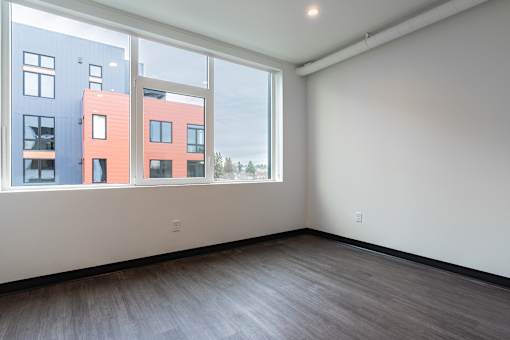 Empty room with a view of apartment buildings outside the window.