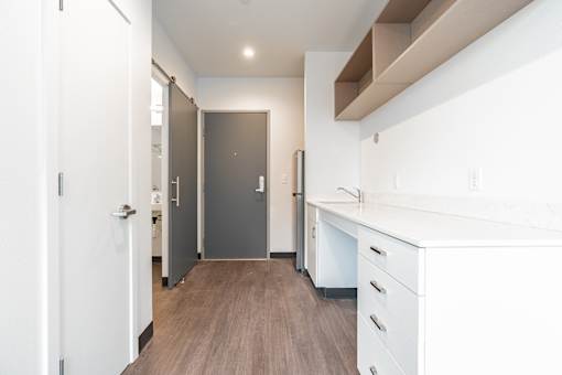 A kitchen with white cabinets and a wooden floor.