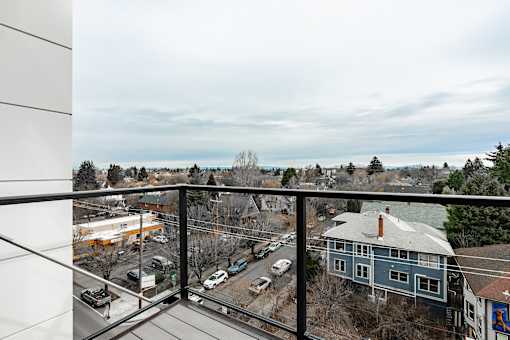 A view from a balcony overlooking a parking lot and buildings.