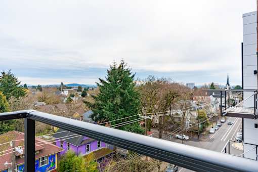 A view from a balcony overlooking a street with cars and buildings.
