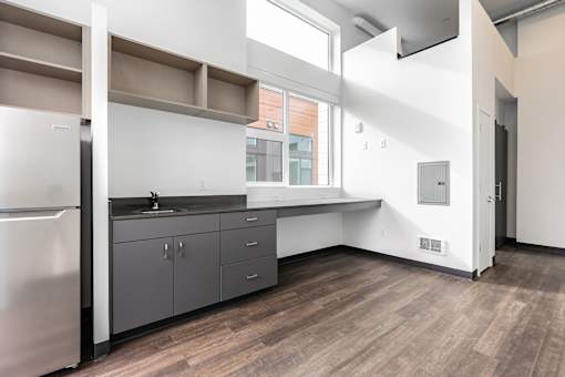 A kitchen with a refrigerator, cabinets, and a window.