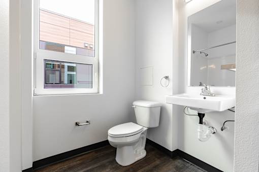 A white toilet sits in a bathroom next to a sink and a mirror.