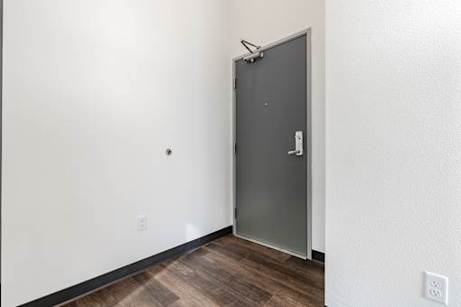 A room with a closed grey door and a white wall.