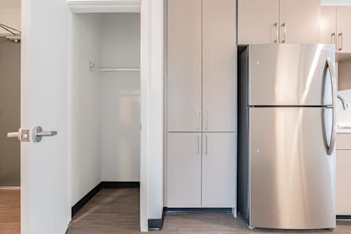 A kitchen with a refrigerator, cabinets, and a doorway leading to another room.