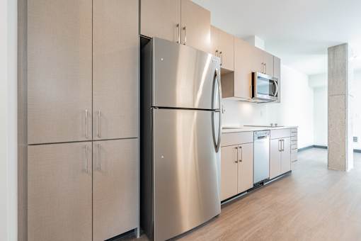 A modern kitchen with a stainless steel refrigerator and cabinets.