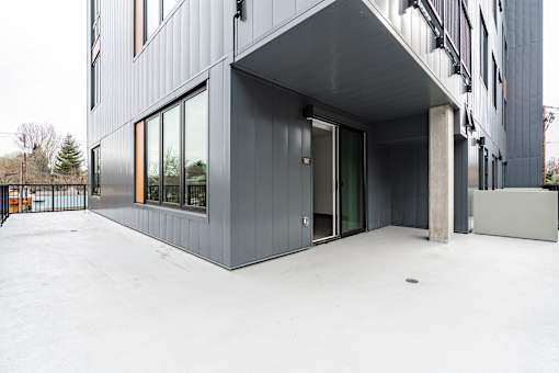 A modern building with a grey facade and a black gate.