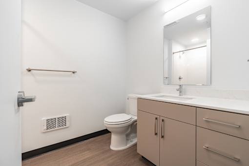 A white bathroom with a toilet, sink, and a mirror.