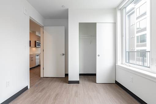 A white hallway with a door on the left and a window on the right.