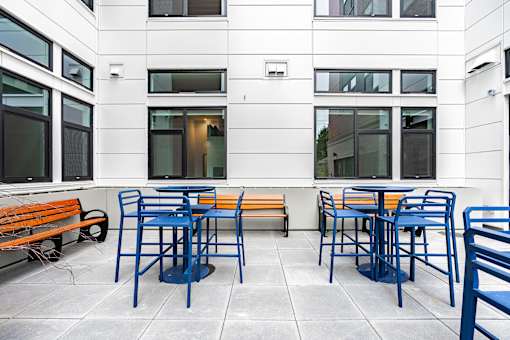 A patio with blue chairs and orange benches.