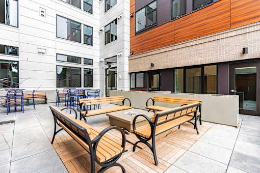 A wooden bench sits on a patio in front of a building.