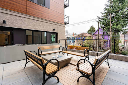 A wooden bench sits on a patio in front of a building.