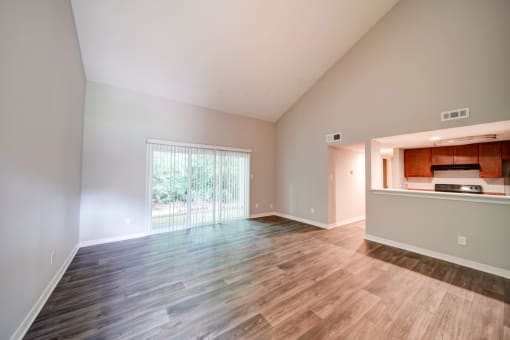an empty living room with a kitchen in the background