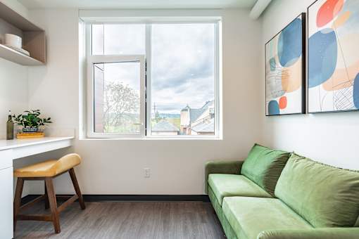 A living room with a green couch and a painting on the wall.