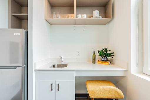 A kitchen with a white countertop and a yellow chair.