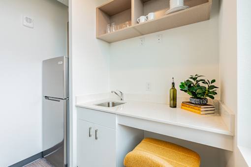 A kitchen with a white counter and a yellow stool.